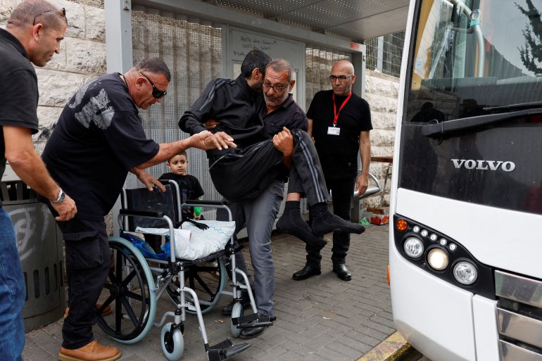 A man carries a patient as other patients from Gaza who have been receiving treatment at Makassed Hospital wait to be transported by bus to the Israeli-occupied West Bank, after they were refused permission to stay, in East Jerusalem November 13, 2023. REUTERS/James Oatway